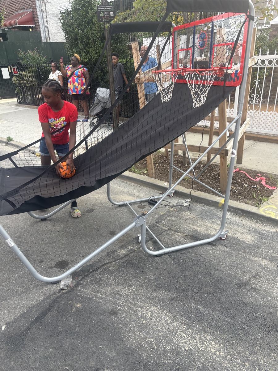 A kid holding a basketball at the hoop set up on the block